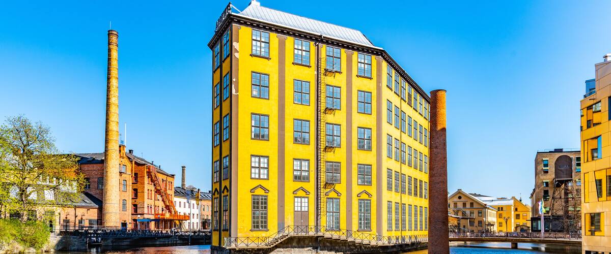 A yellow building with a brick chimney, a bridge, and a river.