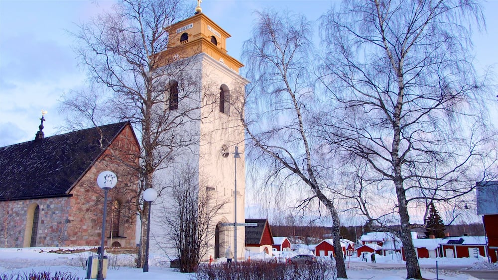 A church with a tall tower, a stone building, and snow-covered houses.