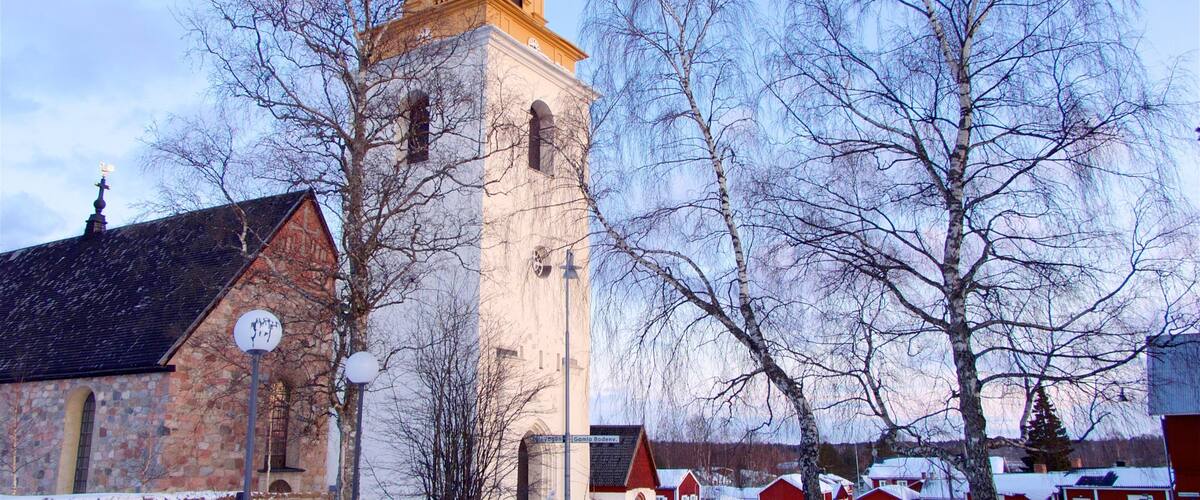 A church with a tall tower, a stone building, and snow-covered houses.