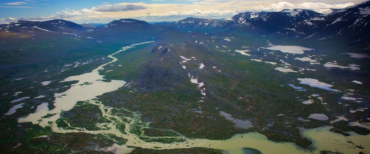 A river winding through a mountainous landscape with patches of snow.