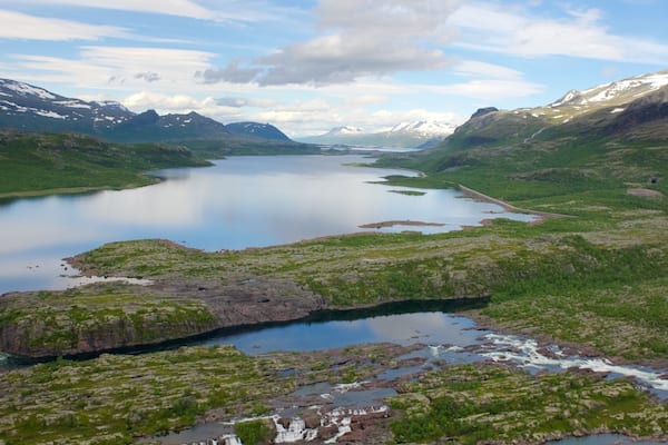A glacial lake surrounded by mountains and greenery.