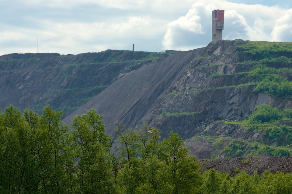 Een bergachtig landschap met een opvallende rode en witte toren op een heuvel.