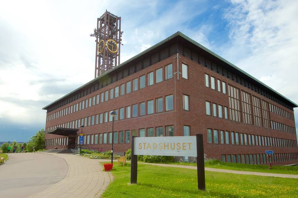 A modern building with a sign reading "STADSHUSET" and a clock tower in the background.