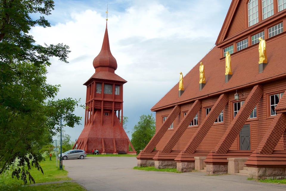Een gebouw van rode baksteen met een toren en gouden beelden.