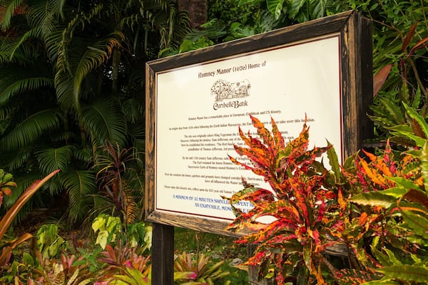 A historical sign about Romney Manor (1626) in a lush garden.