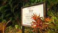 A historical sign about Romney Manor (1626) in a lush garden.