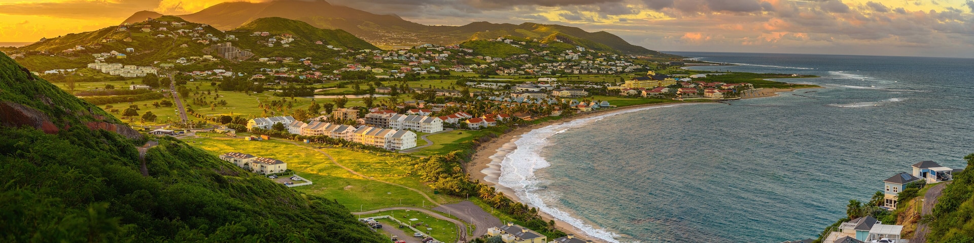 Un pueblo costero con una playa, casas y montañas al fondo.