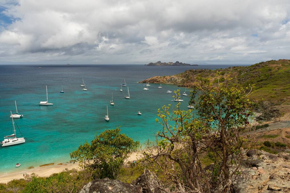A coastal area with turquoise waters, boats, and a sandy beach.