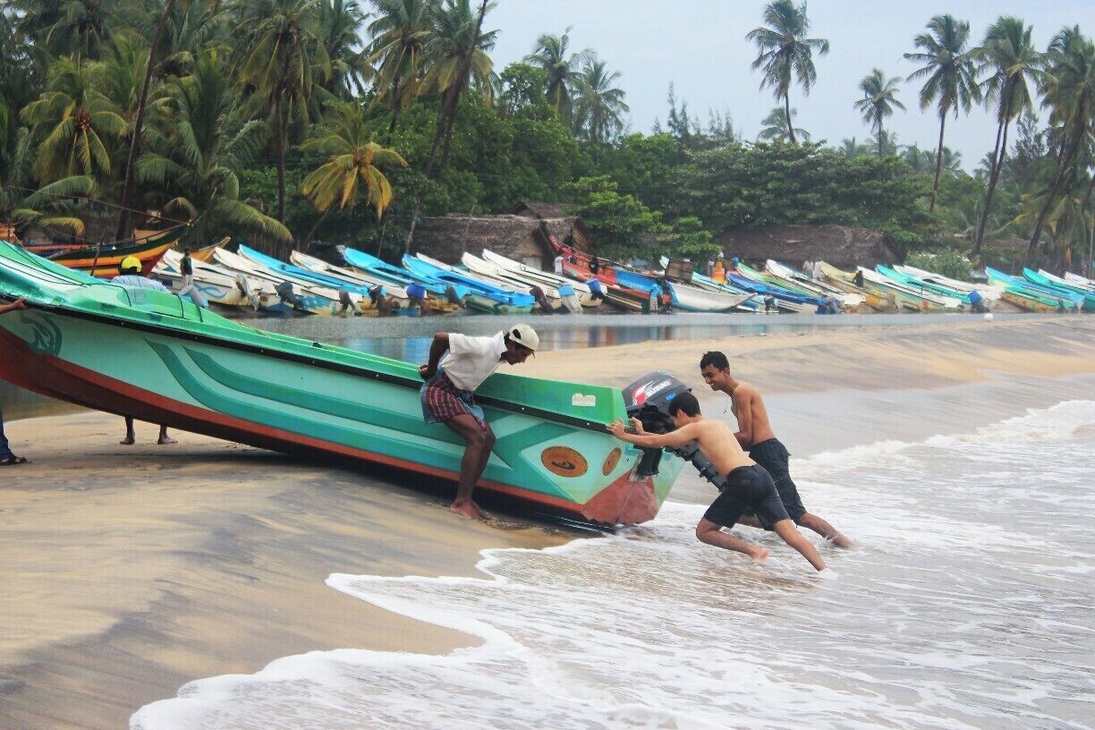 My travelling mate Minul Tennakoon pushes a fishing boat away from the sea with fisherman. 
Arugambay is the best place for sea surfing. It is also known as the Surfers paradise of Sri Lanka. So, many tourists who love sea bathing and surfing visit this place.