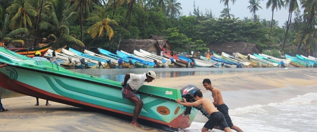 My travelling mate Minul Tennakoon pushes a fishing boat away from the sea with fisherman. 
Arugambay is the best place for sea surfing. It is also known as the Surfers paradise of Sri Lanka. So, many tourists who love sea bathing and surfing visit this place.