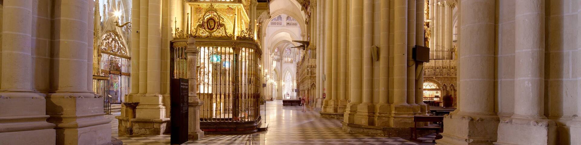 A cathedral interior with high vaulted ceilings, ornate chandeliers, and a checkered floor.