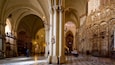 A cathedral interior with high vaulted ceilings, ornate columns, and detailed wall sculptures.