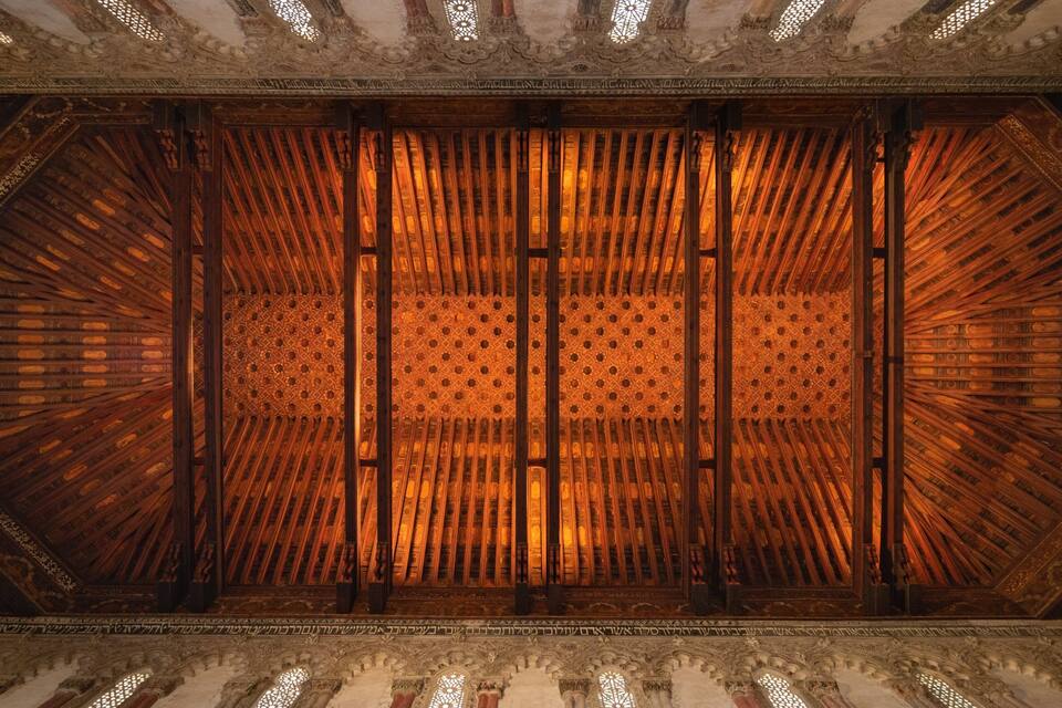 Un techo de madera ornamentado con delicados grabados y un patrón geométrico.