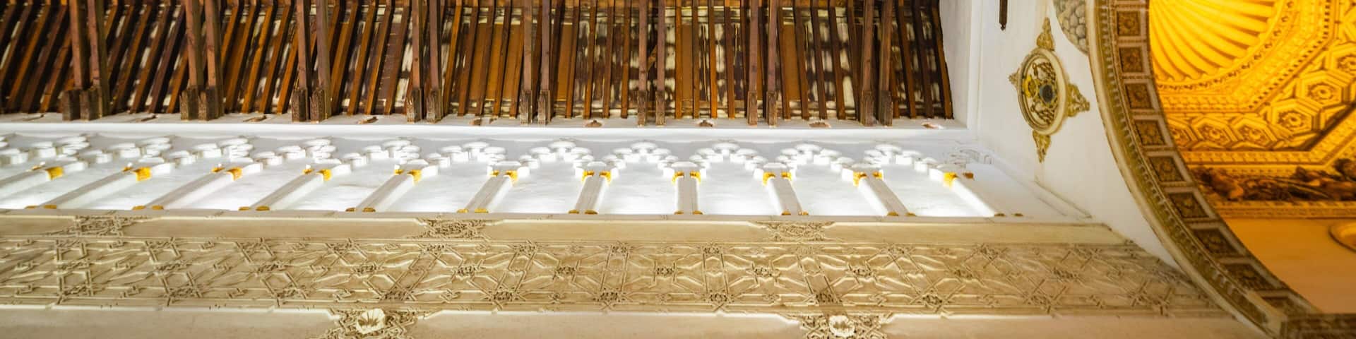 A cathedral interior with ornate wooden beams, white columns, and a golden dome.