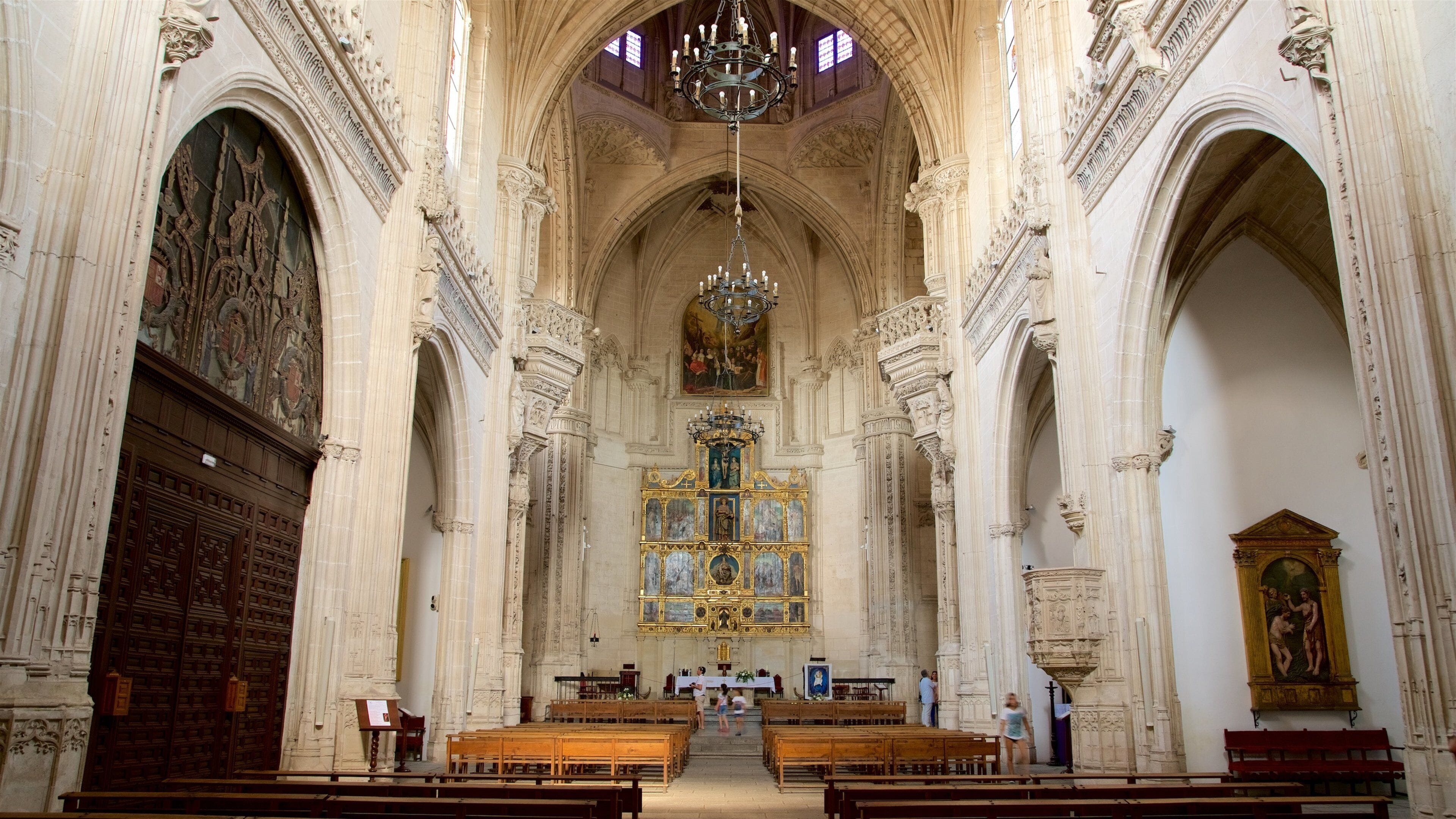 Een statig kathedraalinterieur met hoge gewelfde plafonds, versierde zuilen en een centraal altaar.