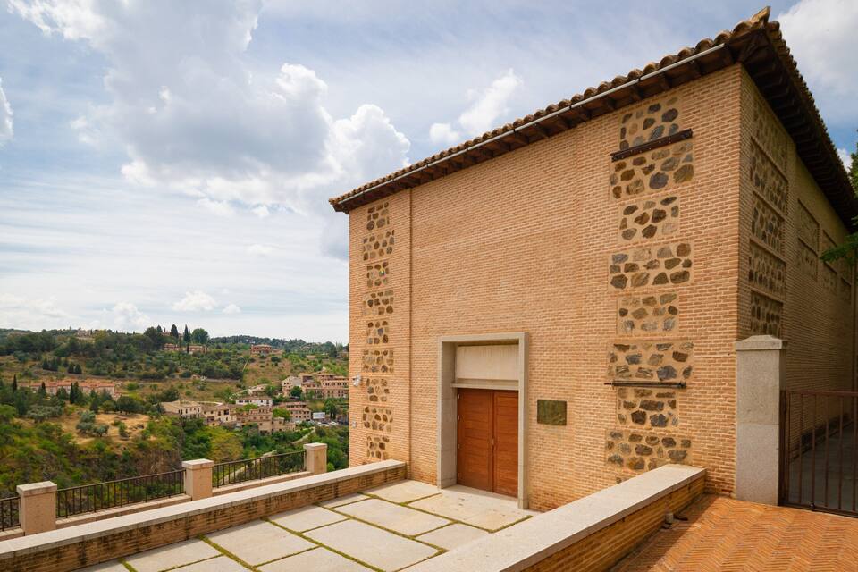 Un bâtiment en briques avec un toit en tuiles, une porte en bois et des éléments décoratifs en pierre.