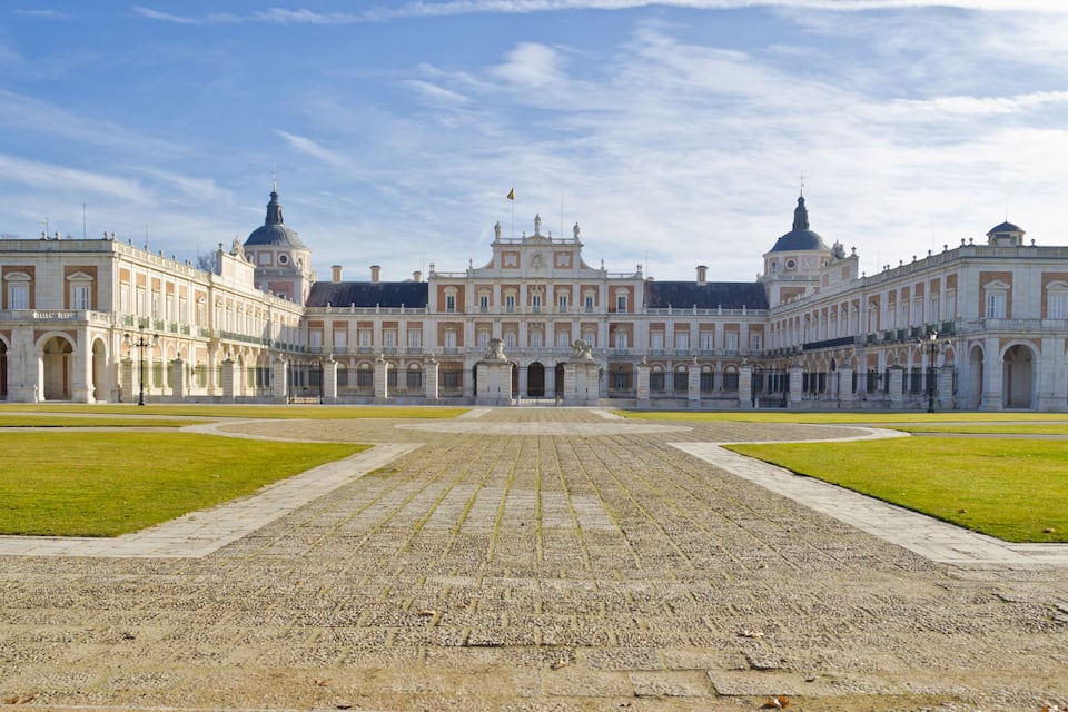 Un imposant bâtiment historique à l’architecture symétrique, doté d’une cour intérieure et surplombant un ciel dégagé.