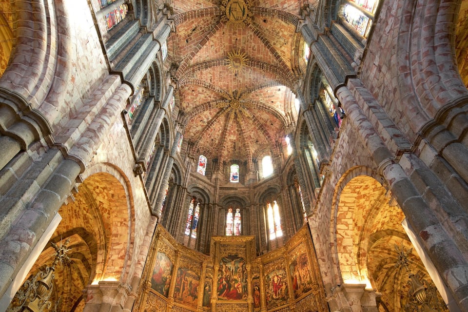 An ornate cathedral interior with high vaulted ceilings, stained glass windows, and intricate stone carvings.