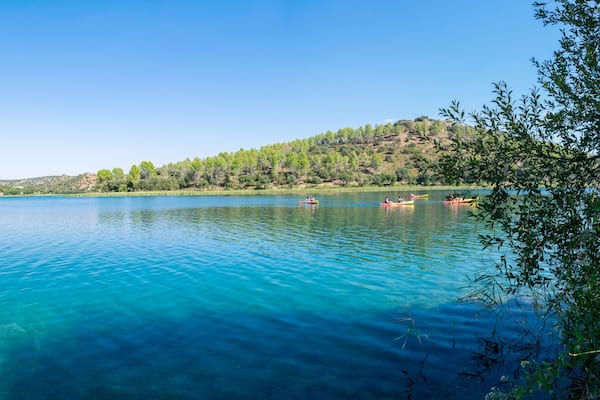Un lac aux eaux limpides, entouré de collines et d’arbres.
