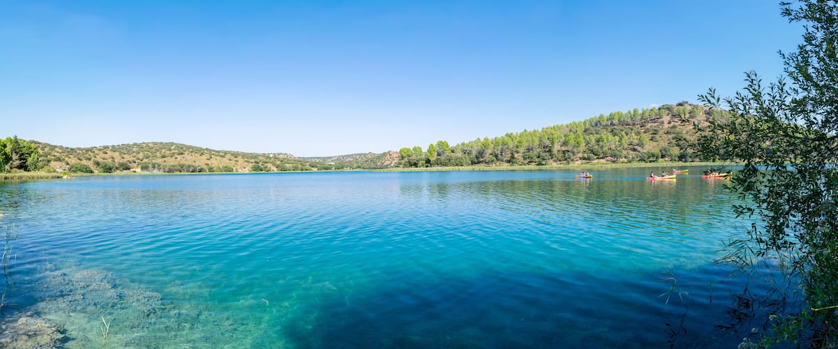 A clear lake surrounded by hills and trees.
