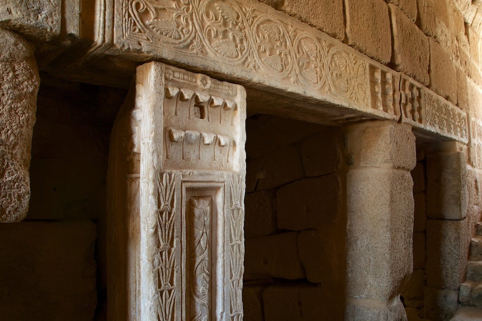 A stone column with intricate carvings and a staircase.