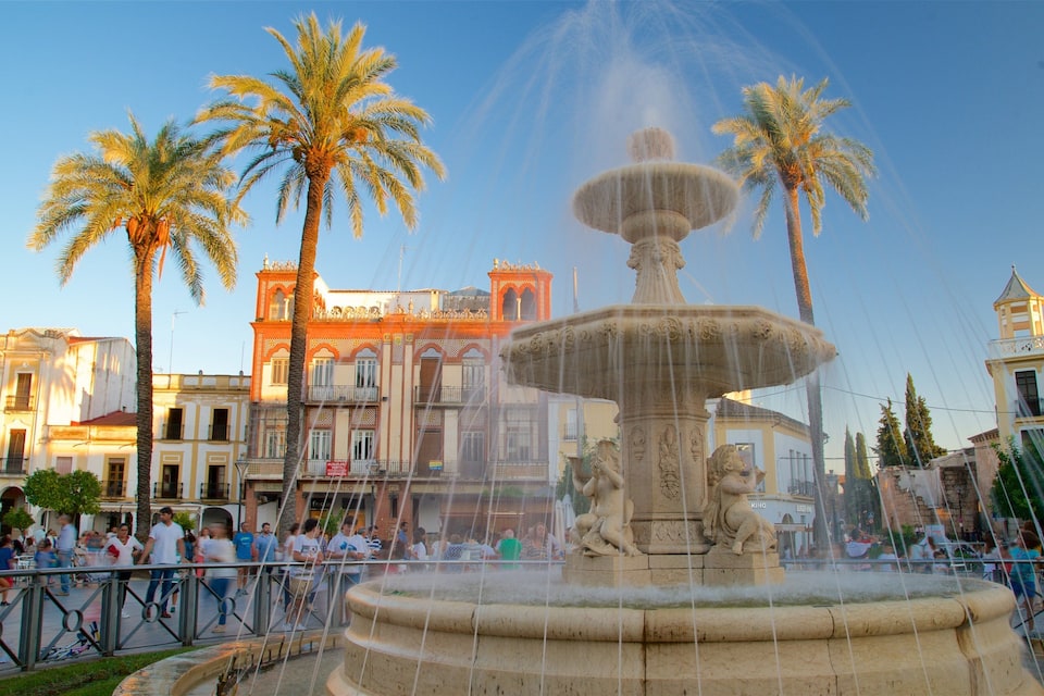 A historic fountain with lions, palm trees, and classic architecture in a public square.