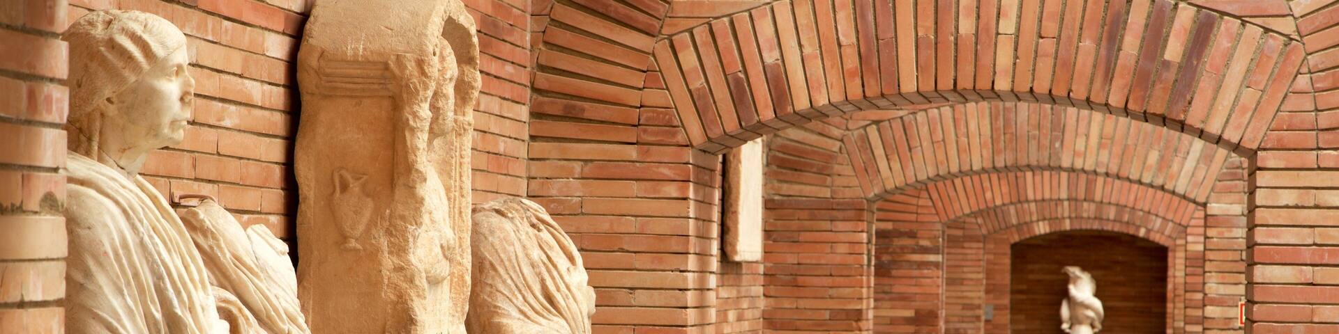 Un pasillo con estatuas clásicas y arcos de ladrillo.