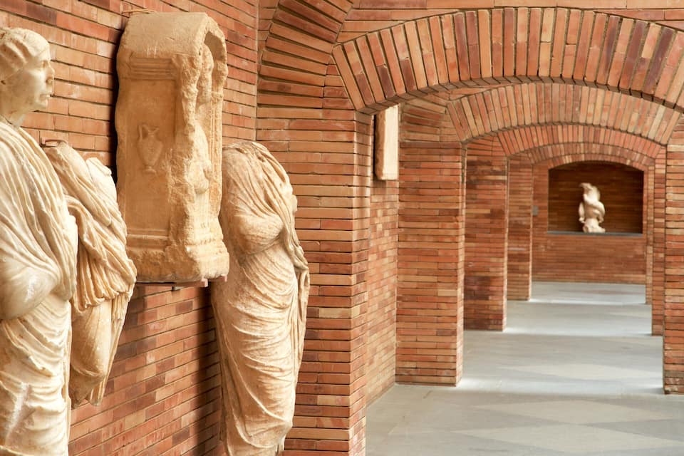 Un pasillo con estatuas clásicas y arcos de ladrillo.