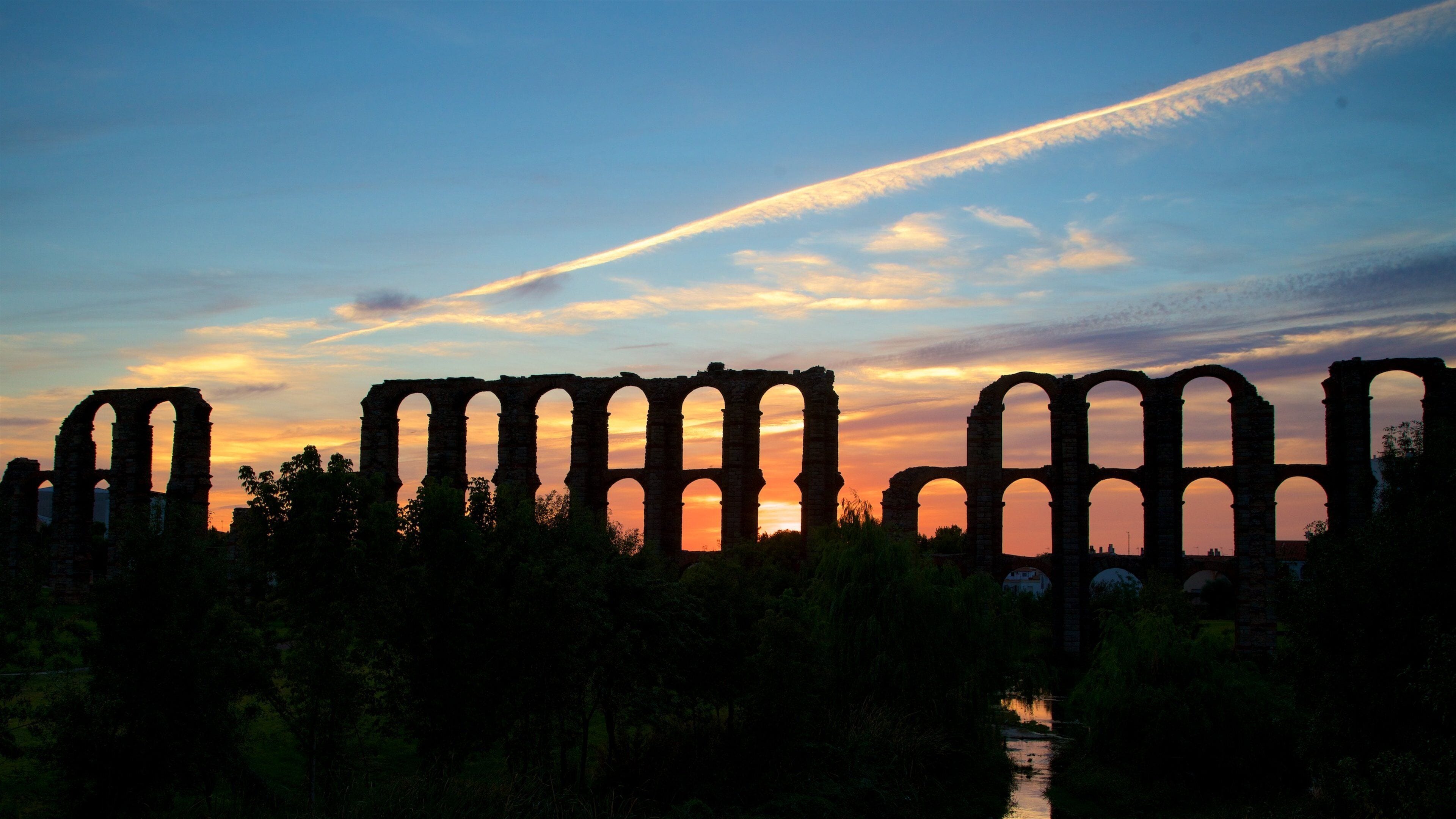 Acueducto de los Milagros featuring heritage architecture and a sunset
