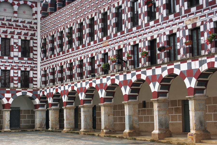 Un edificio con patrones rojo y blanco a cuadros y puertas en arco.