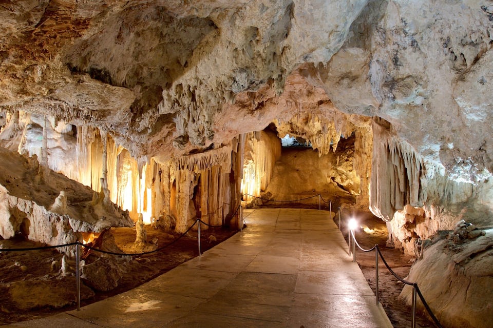 Eine Höhle mit Stalaktiten und Stalagmiten, beleuchtet durch künstliches Licht.