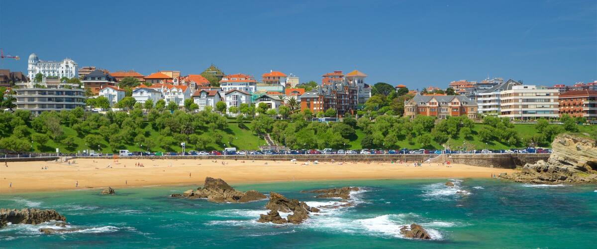 A coastal town with a sandy beach, rocky shoreline, and a backdrop of colorful buildings.