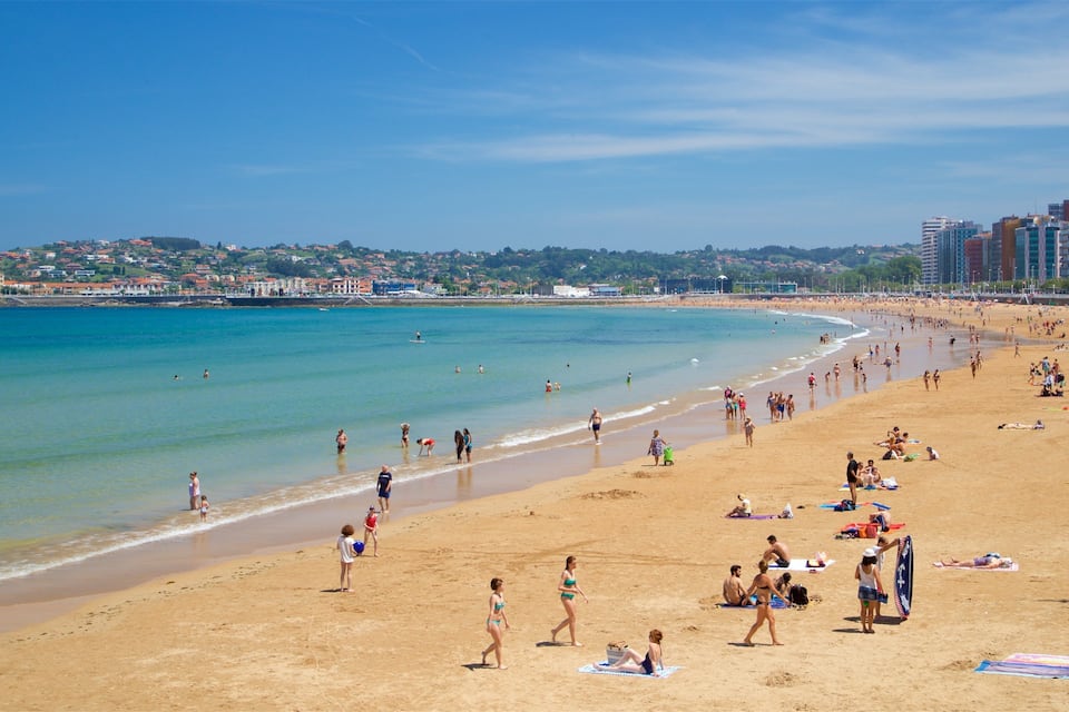 A crowded beach with people sunbathing and swimming.