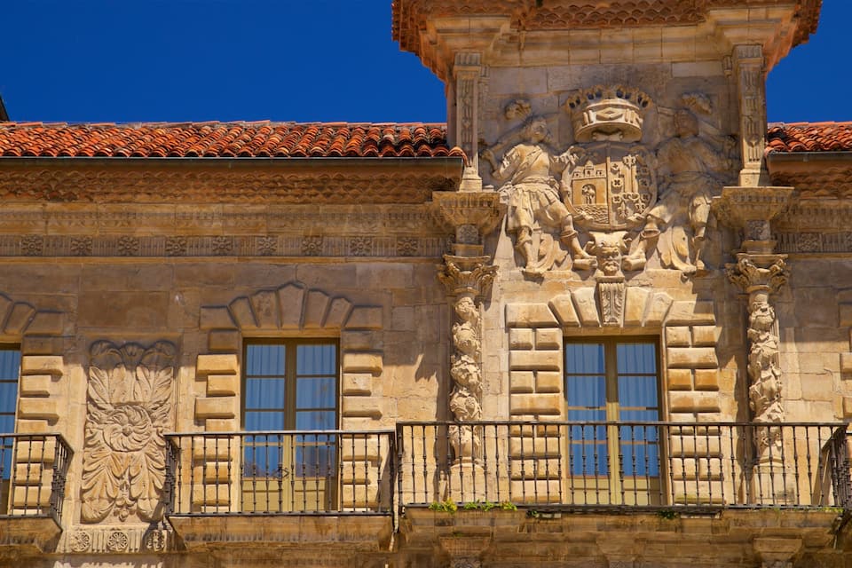 Un bâtiment orné de sculptures en pierre, doté d’un toit en tuiles et d’un balcon avec une balustrade en fer forgé.