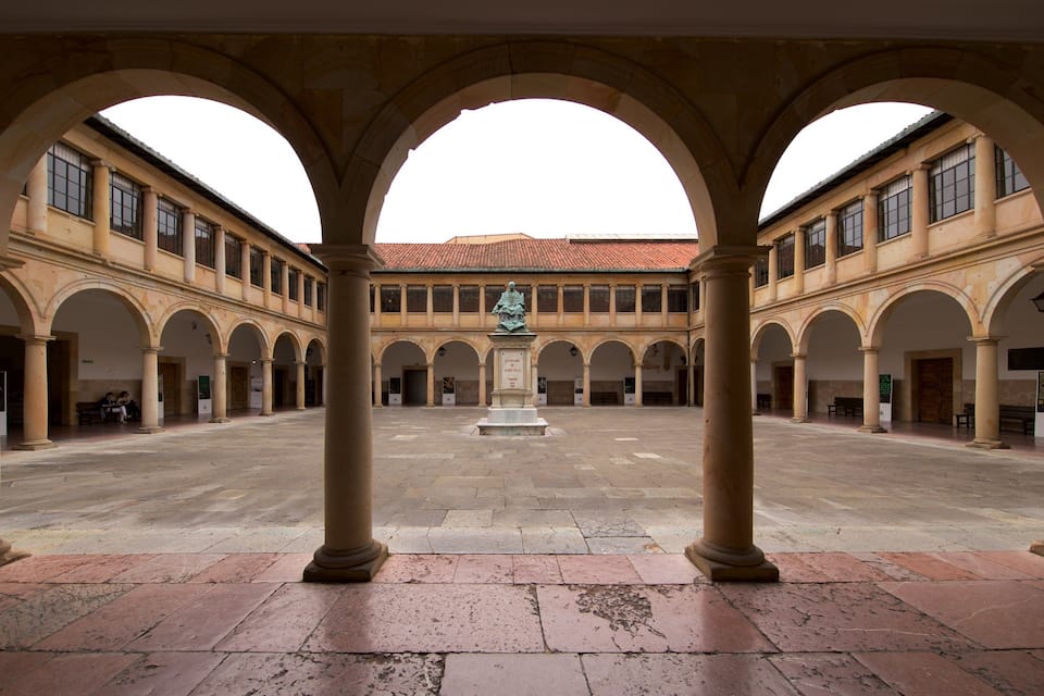 A courtyard with arches, a statue, and a tiled roof.