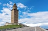 Een hoge stenen toren met een koepel, gelegen op een groene heuvel met een stenen trap die er naartoe leidt.