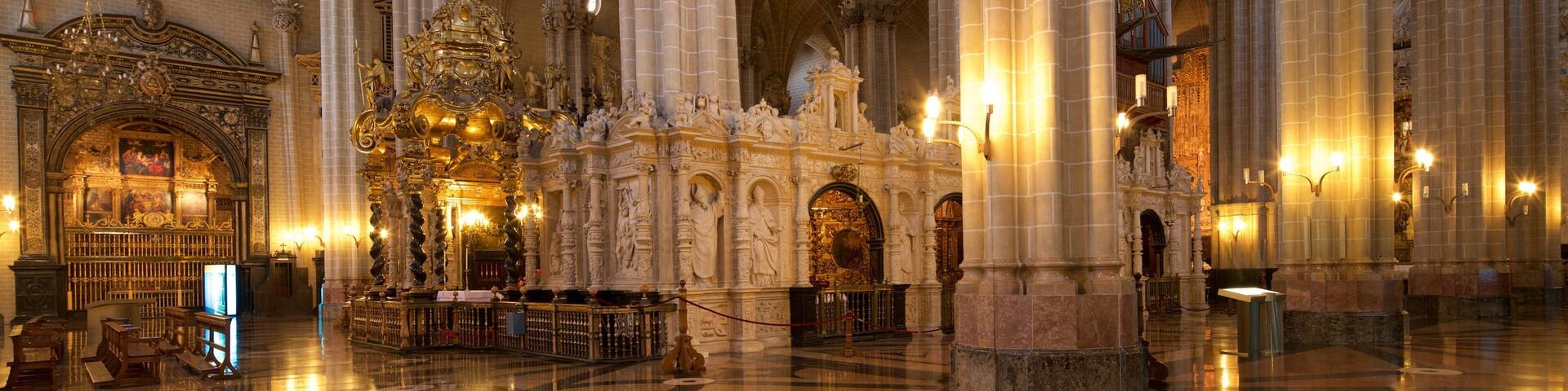 A grand cathedral interior with high vaulted ceilings, ornate columns, and a richly decorated altar.