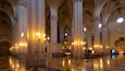A grand cathedral interior with high vaulted ceilings, ornate columns, and a central altar.