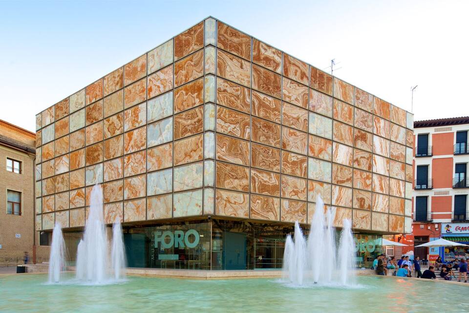 Een modern gebouw met een marmeren gevel en een fontein ervoor.