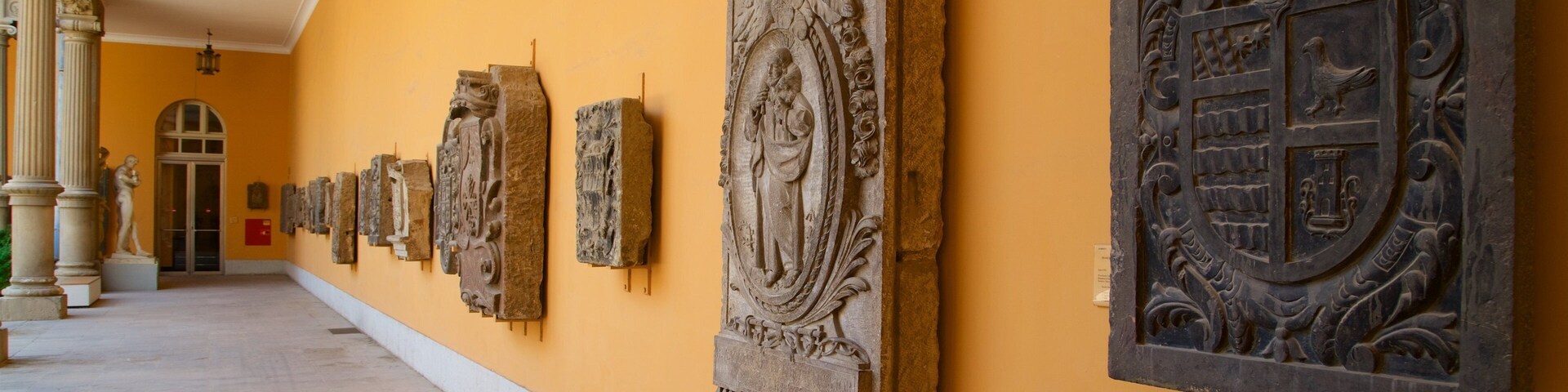 A row of stone carvings on a yellow wall in a corridor.