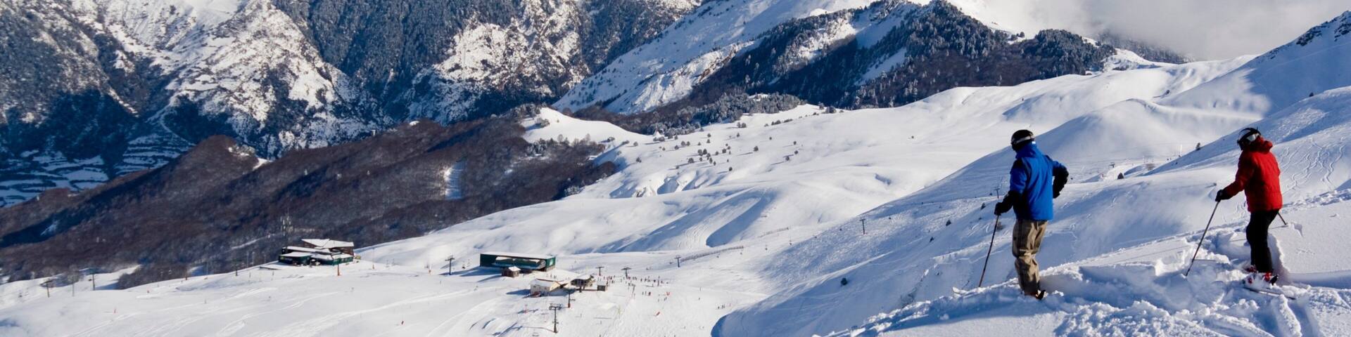 A snowy mountain landscape with skiers, a ski lift, and a clear sky.