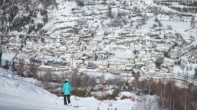 Un pueblo cubierto de nieve con casas y una persona esquiando por una pendiente.