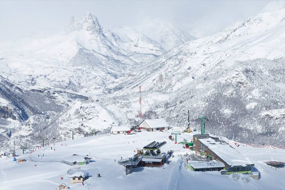 A snow-covered mountain with ski lifts and buildings.