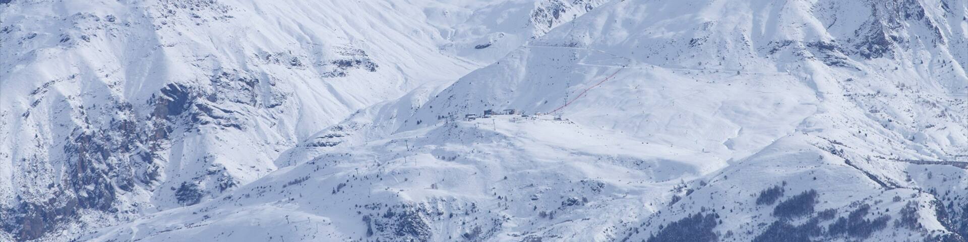 A snow-covered mountain range with sharp peaks and deep valleys.