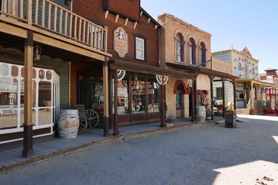 Calle histórica con edificios de madera, tiendas antiguas y un pasaje cubierto.