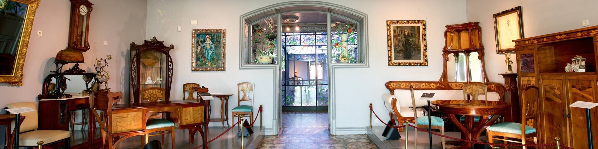 A grand hallway with ornate furniture, a large mirror, and a stained glass window.