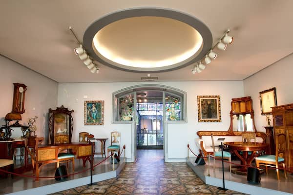 Un vaste hall d’entrée agrémenté de meubles richement décorés, d’un grand miroir et d’une fenêtre à vitraux.