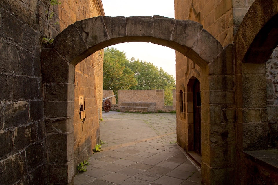 An arched stone pathway leading through a historic building with a cannon visible in the distance.