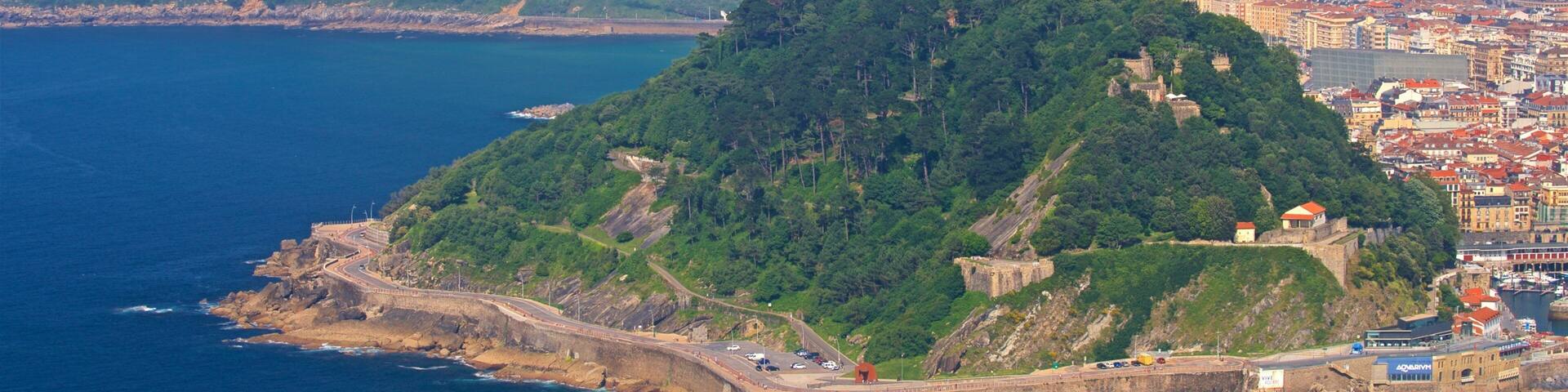 A coastal city with a prominent hilltop fortress and a winding road along the shoreline.