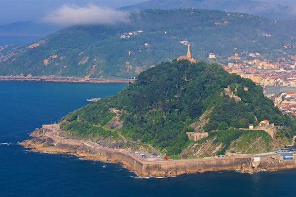 A coastal city with a prominent hilltop fortress and a winding road along the shoreline.